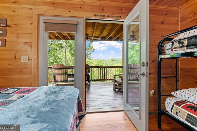 bedroom featuring wood ceiling, wooden walls, access to outside, and light hardwood / wood-style floors