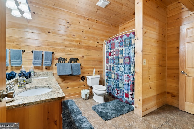 bathroom featuring vanity, toilet, wooden walls, and tile patterned flooring