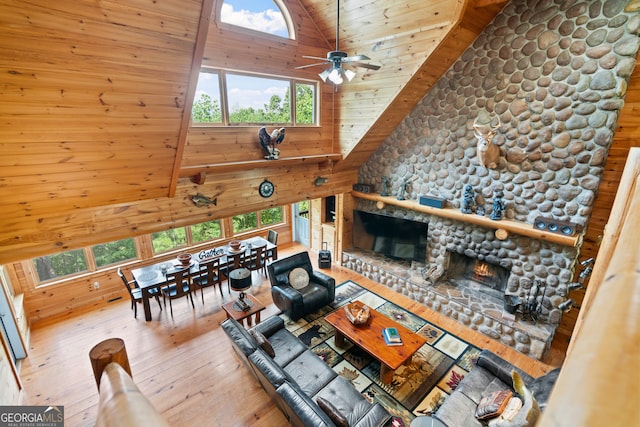 living room featuring wooden ceiling, a fireplace, high vaulted ceiling, ceiling fan, and light wood-type flooring