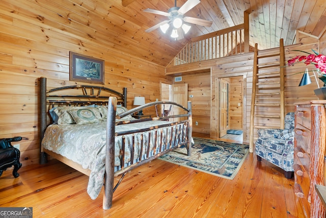 bedroom with high vaulted ceiling, hardwood / wood-style floors, wood walls, ceiling fan, and wooden ceiling