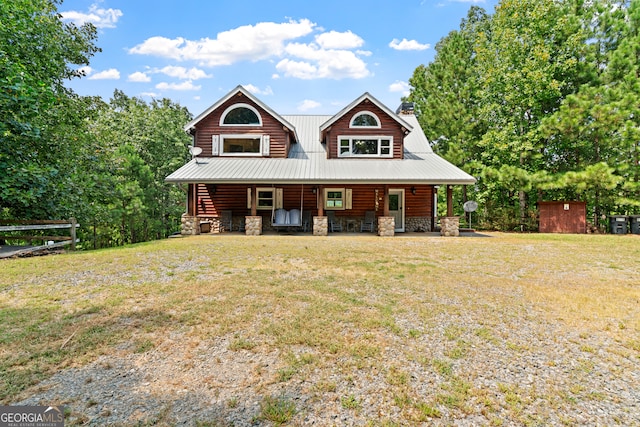 log-style house featuring covered porch, a front lawn, and a storage unit