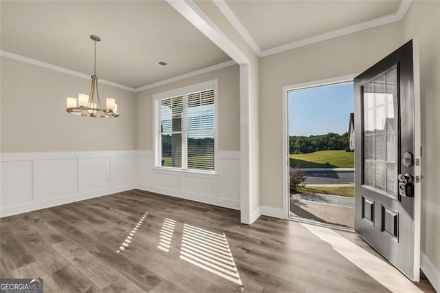 unfurnished dining area featuring ornamental molding, wood-type flooring, and an inviting chandelier