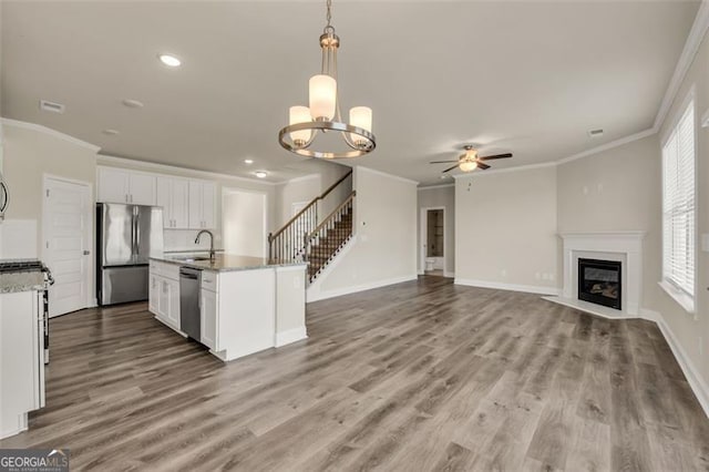 kitchen featuring ceiling fan with notable chandelier, appliances with stainless steel finishes, a wealth of natural light, an island with sink, and pendant lighting