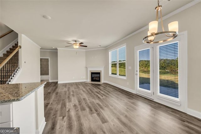 unfurnished living room with ornamental molding, ceiling fan with notable chandelier, and hardwood / wood-style flooring