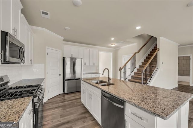 kitchen with appliances with stainless steel finishes, a center island with sink, white cabinetry, and sink