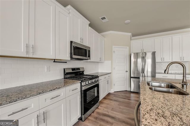 kitchen with white cabinets, stainless steel appliances, sink, wood-type flooring, and ornamental molding