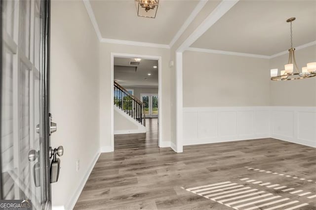 entrance foyer with wood-type flooring, a notable chandelier, and ornamental molding