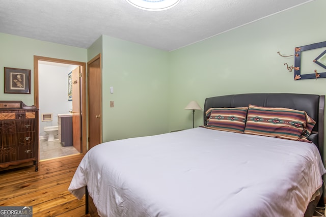 bedroom with hardwood / wood-style floors, connected bathroom, and a textured ceiling