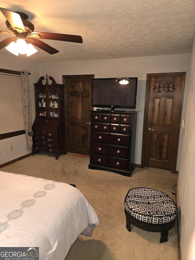 bedroom with baseboards, a textured ceiling, ceiling fan, and light carpet