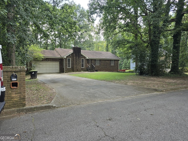single story home with concrete driveway, a front yard, brick siding, a garage, and a chimney