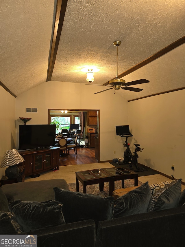 living room featuring lofted ceiling with beams, ceiling fan, hardwood / wood-style floors, and a textured ceiling