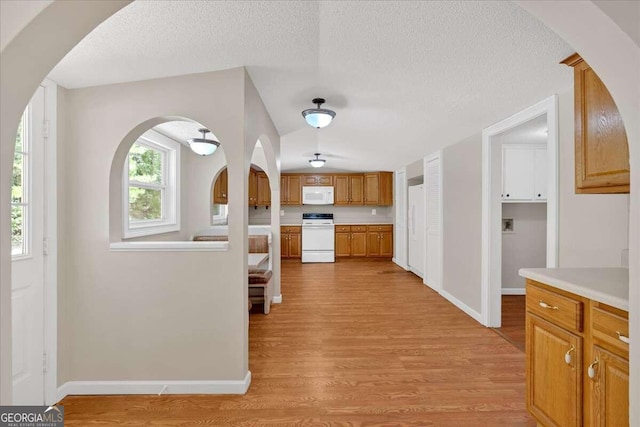 interior space with a textured ceiling, light wood-type flooring, and white appliances