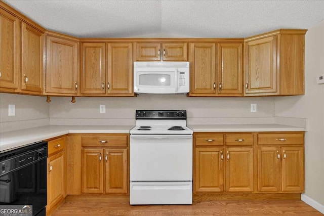 kitchen with light wood-type flooring, white appliances, vaulted ceiling, and a textured ceiling