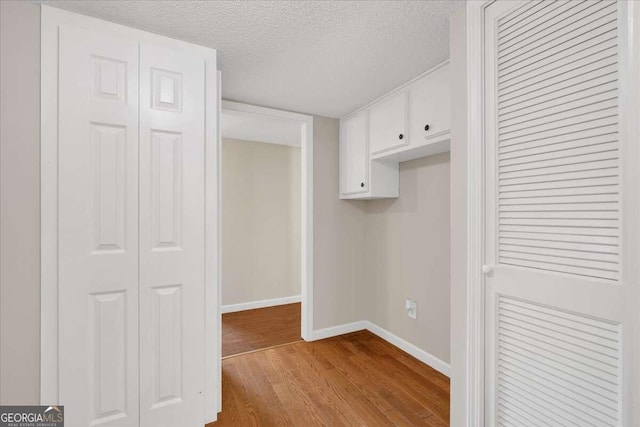 interior space featuring white cabinets, light hardwood / wood-style floors, and a textured ceiling