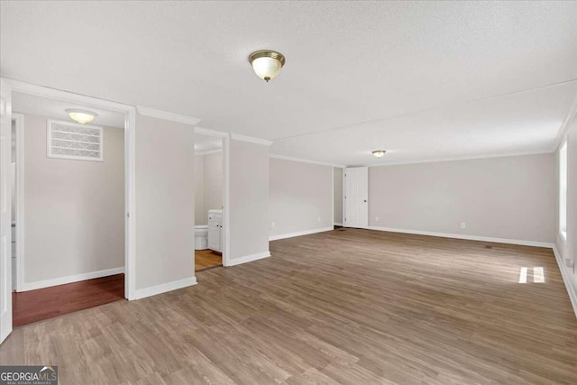 interior space featuring a textured ceiling, crown molding, and wood-type flooring