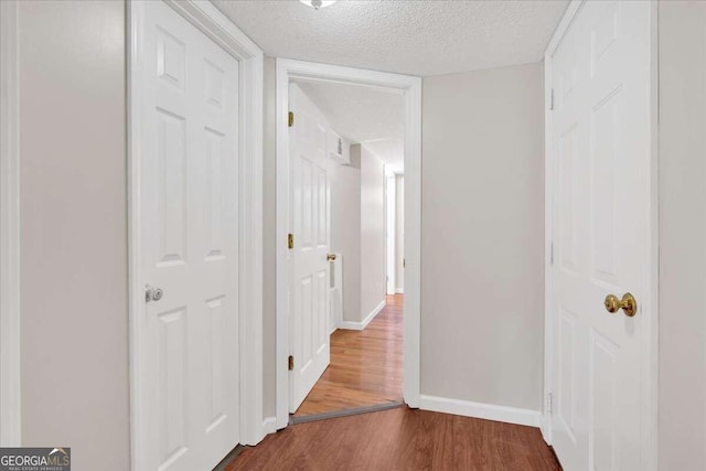 hall with hardwood / wood-style flooring and a textured ceiling