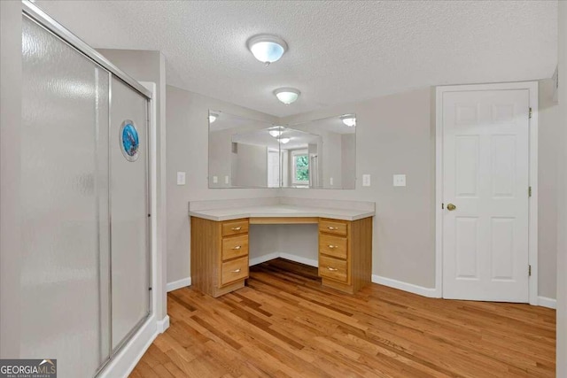 bathroom featuring vanity, a textured ceiling, hardwood / wood-style floors, and a shower with shower door