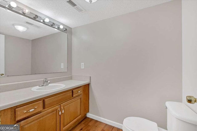 bathroom featuring a textured ceiling, vanity, toilet, and wood-type flooring