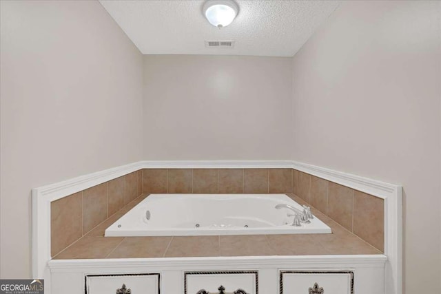 bathroom featuring a textured ceiling and tiled bath