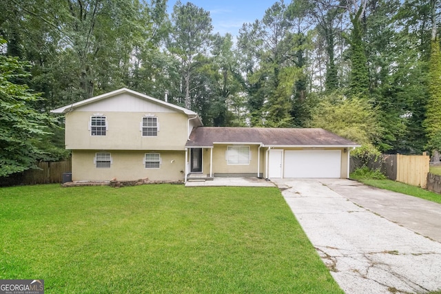 tri-level home with driveway, a garage, fence, a front lawn, and stucco siding