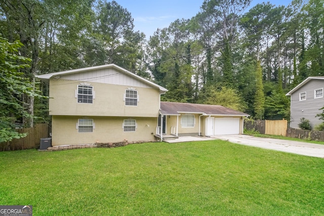 tri-level home with a front yard, fence, driveway, and an attached garage