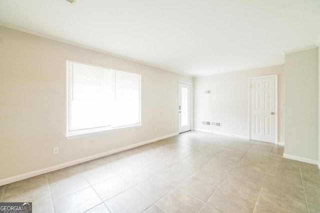 empty room with baseboards, light tile patterned floors, and crown molding