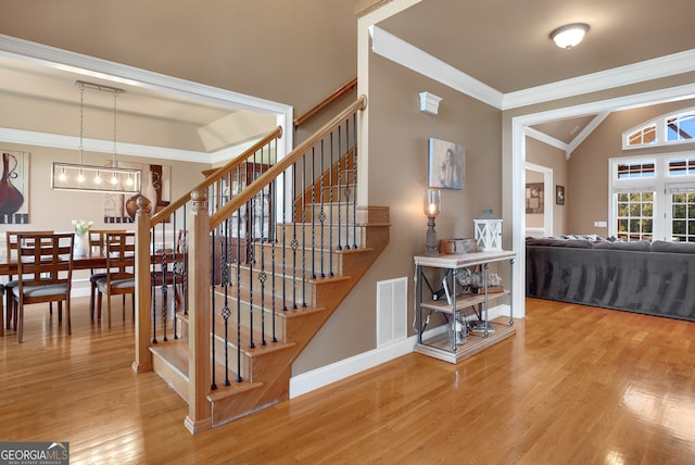 stairs with crown molding, vaulted ceiling, and hardwood / wood-style floors