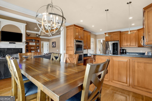 dining area featuring a premium fireplace, a chandelier, crown molding, and light hardwood / wood-style flooring