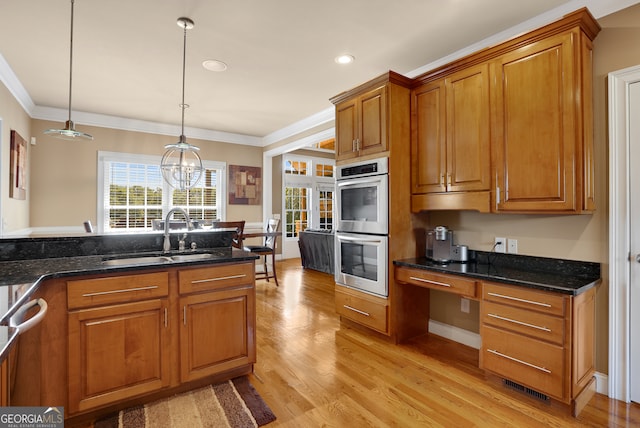 kitchen featuring light wood-type flooring, decorative light fixtures, an inviting chandelier, sink, and appliances with stainless steel finishes