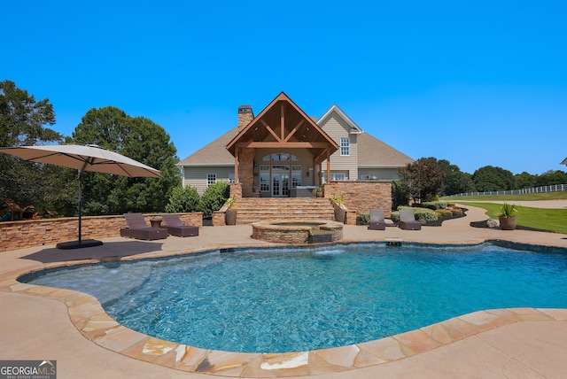 view of swimming pool with pool water feature, a patio area, and french doors