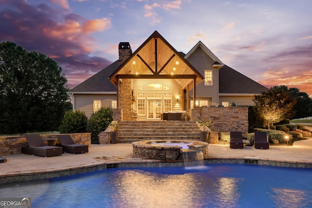 pool at dusk featuring a patio area, an in ground hot tub, pool water feature, an outdoor hangout area, and french doors