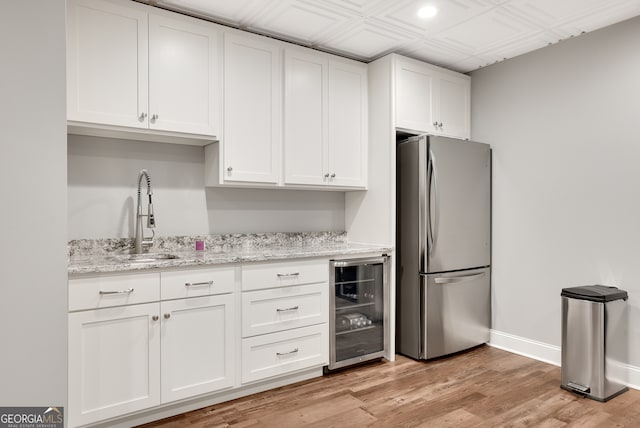 kitchen featuring light hardwood / wood-style flooring, wine cooler, stainless steel fridge, and white cabinetry