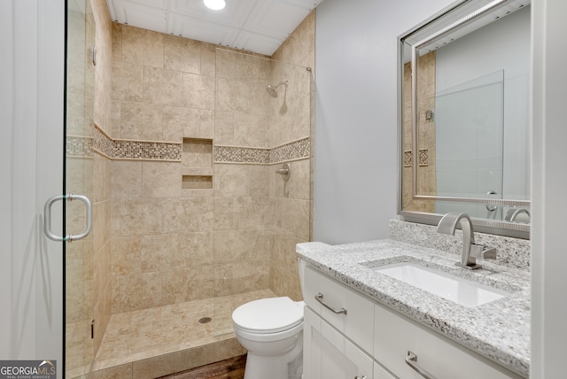 bathroom with hardwood / wood-style floors, toilet, a shower with door, and vanity