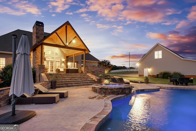 pool at dusk with a patio area, an in ground hot tub, and french doors