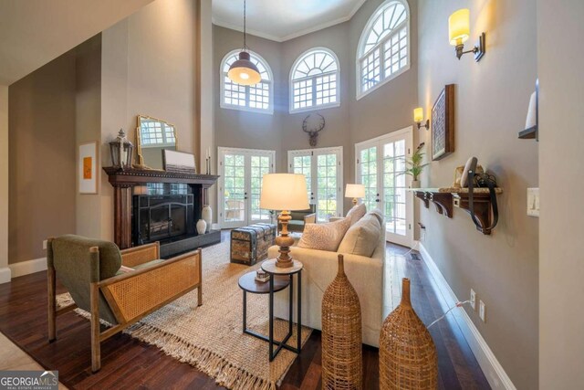 living room with hardwood / wood-style floors, crown molding, and a towering ceiling