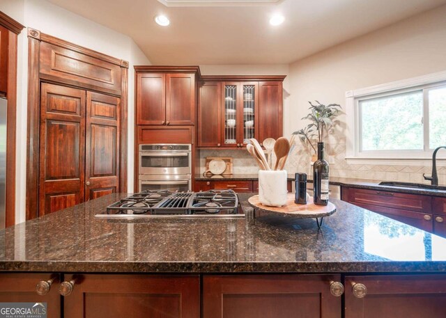 kitchen with dark stone counters, a kitchen island, and backsplash