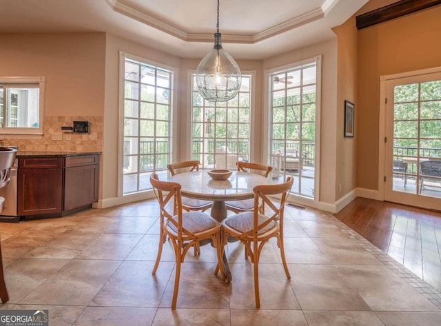 dining area with an inviting chandelier, light hardwood / wood-style flooring, ornamental molding, and a tray ceiling