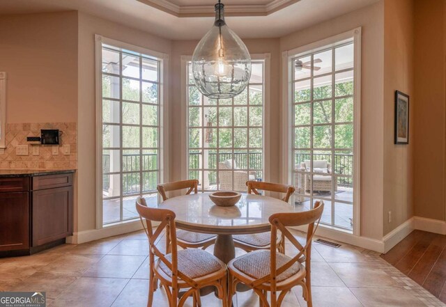 dining room with a wealth of natural light, crown molding, and light hardwood / wood-style flooring