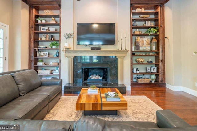 living room with plenty of natural light, dark wood-type flooring, and a high end fireplace