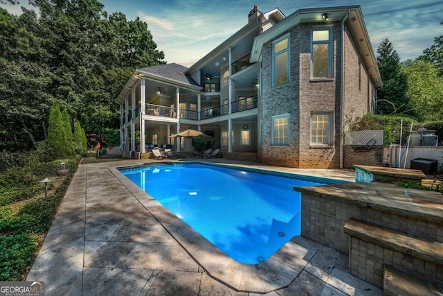 pool at dusk with a patio area