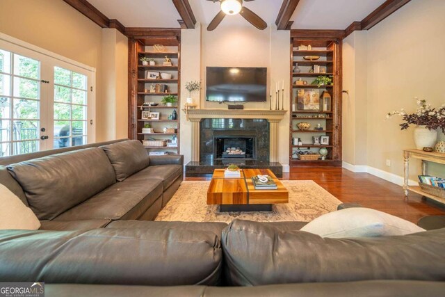 living room featuring ceiling fan, a high end fireplace, hardwood / wood-style floors, and beam ceiling