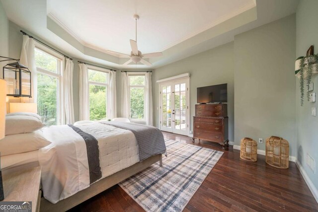 bedroom with a tray ceiling, dark hardwood / wood-style flooring, access to exterior, and ceiling fan