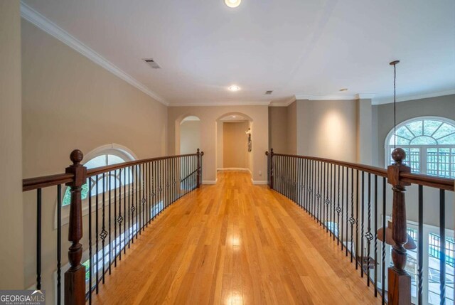 corridor with ornamental molding, a chandelier, and light hardwood / wood-style floors