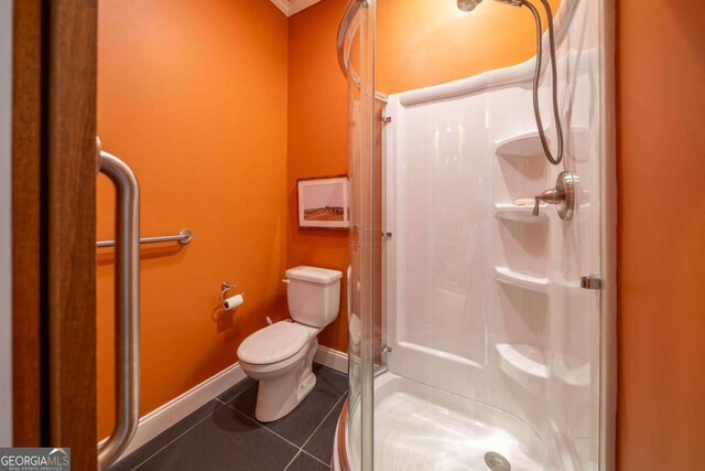 bathroom with toilet, tile patterned floors, and a shower with door