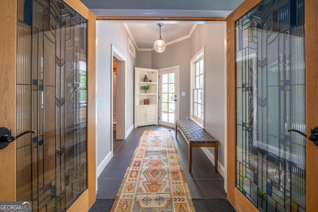 entryway with crown molding and dark tile patterned floors