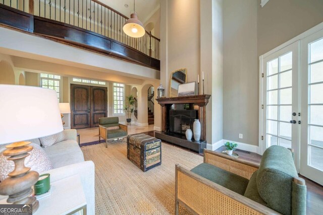 living room featuring french doors, light hardwood / wood-style flooring, and a high ceiling