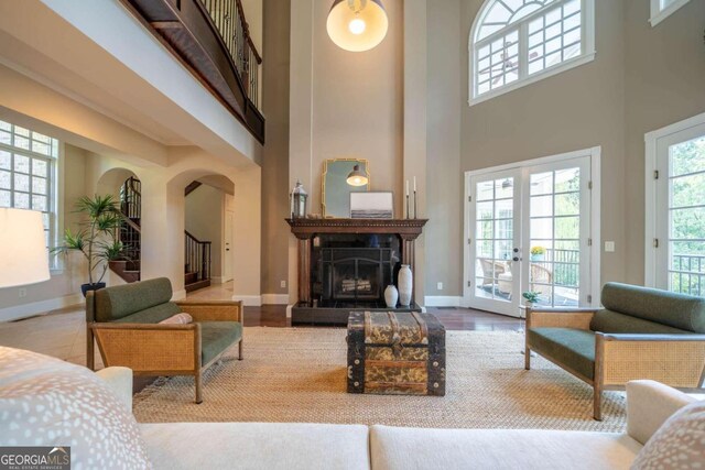 living room with a towering ceiling, wood-type flooring, and french doors