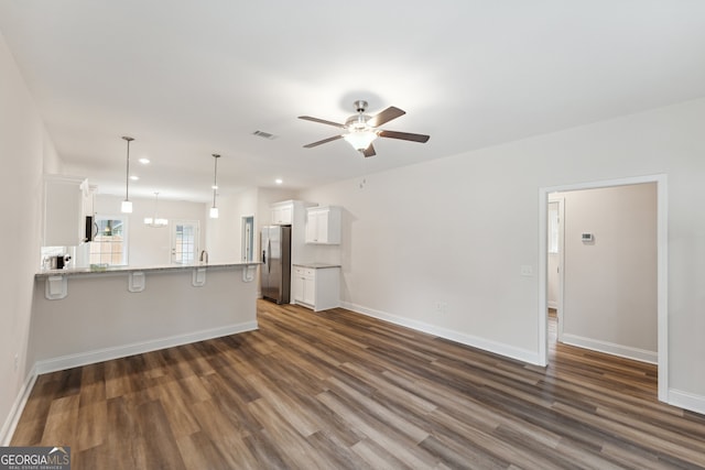 unfurnished living room featuring dark wood-type flooring and ceiling fan