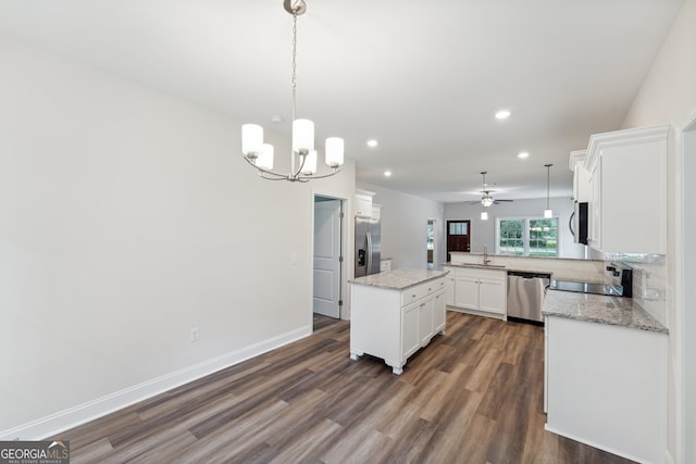 kitchen featuring white cabinets, a center island, ceiling fan with notable chandelier, stainless steel appliances, and kitchen peninsula