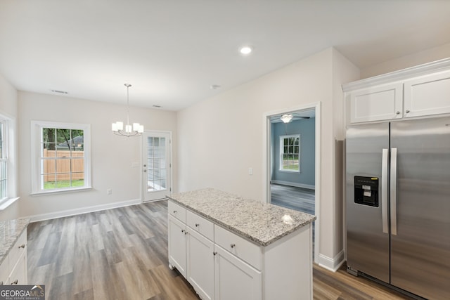 kitchen with a center island, ceiling fan with notable chandelier, white cabinetry, wood-type flooring, and stainless steel fridge with ice dispenser